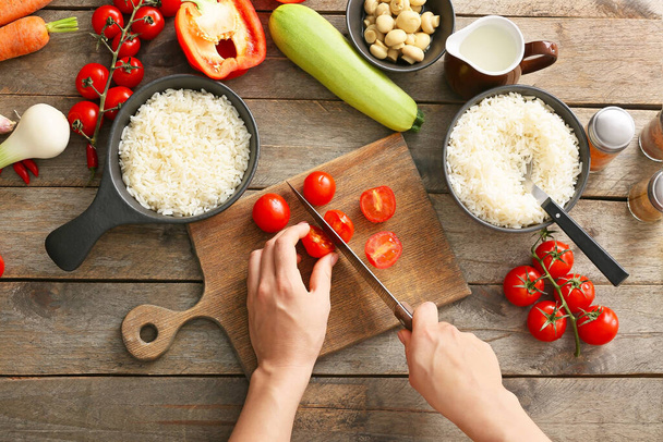 Vrouw snijden groenten voor rijst ovenschotel op tafel, bovenaanzicht - Foto, afbeelding