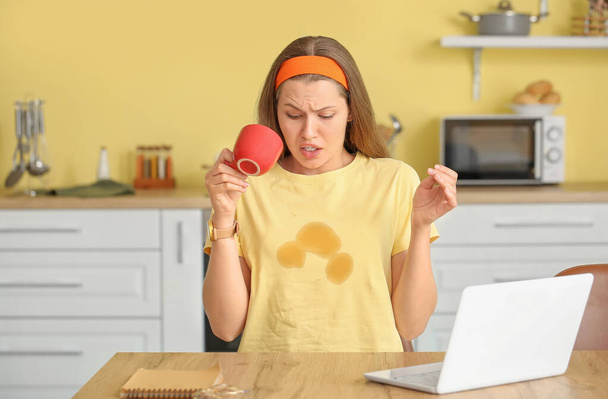 Stressato giovane donna con macchie di caffè sulla sua t-shirt in cucina - Foto, immagini