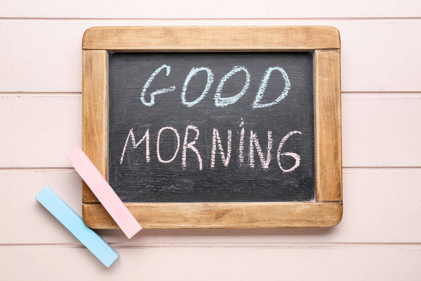 Tiza de colores y pizarra con texto Buenos días sobre fondo de madera - Foto, imagen
