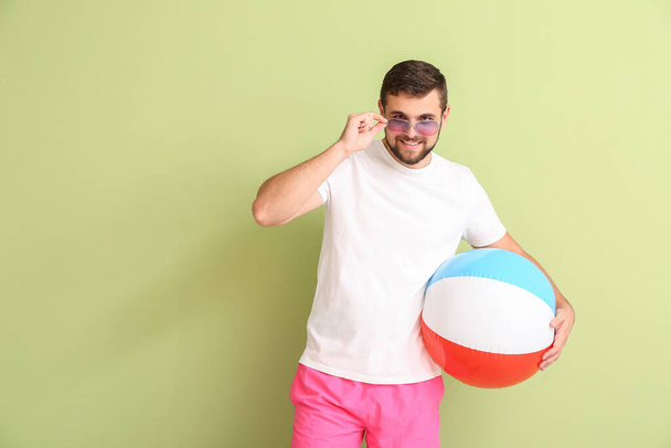 Handsome man with stylish sunglasses and inflatable ball on color background - Φωτογραφία, εικόνα