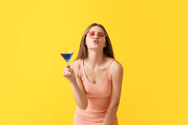 Schöne Frau mit stilvoller Sonnenbrille und Cocktail auf farbigem Hintergrund - Foto, Bild