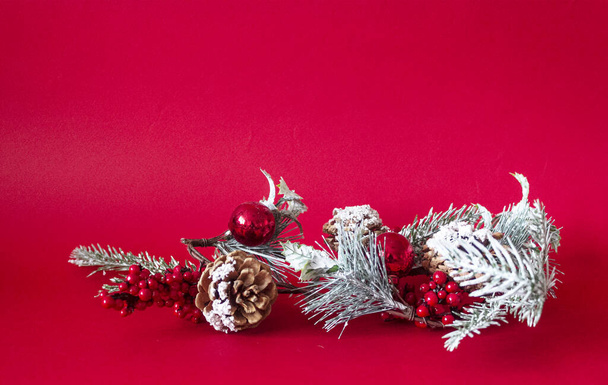Christmas tree branch with decorations on a red background. Place to write - Foto, Imagem