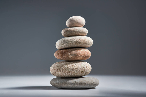 Balancing pyramid of sea pebbles on a gray background, the concept of harmony and balance, heavy and light. Stones in the form of scales with balancing stones. - Foto, Bild