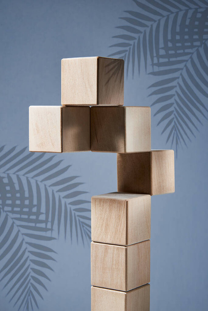 Balancing pyramid of wooden square blocks on a blue background, the concept of harmony and balance, heavy and light. - Foto, Bild