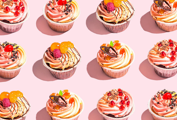 Вкусные красочные кексы на розовом фоне - Фото, изображение