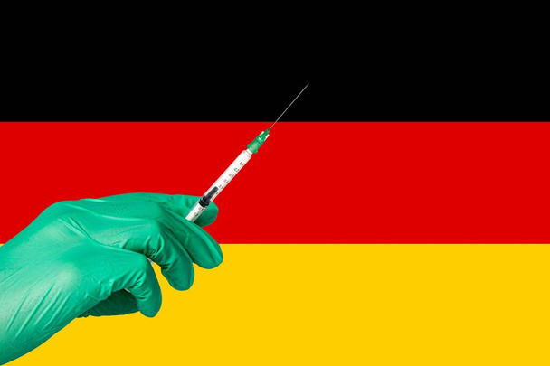 ドイツ国旗の前でコロナワクチンを接種し. - 写真・画像