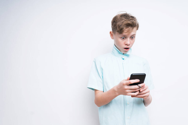 A Caucasian boy is looking surprised by something on the phone - Φωτογραφία, εικόνα