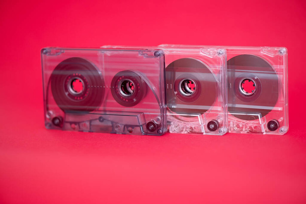 Τρεις πλαστικές κασέτες ηχογράφησης σε κόκκινο φόντο - Φωτογραφία, εικόνα