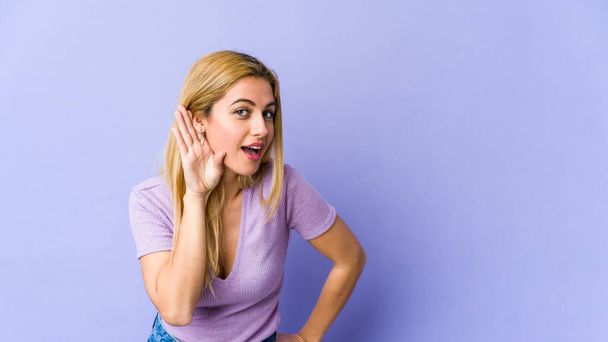 Young blonde caucasian woman trying to listening a gossip. - 写真・画像