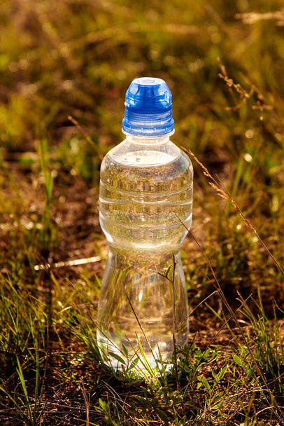 Botella de plástico con agua limpia y transparente en la hierba. - Foto, imagen