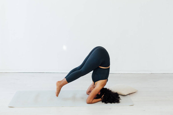 Mooie brunette vrouw yoga asana gymnastiek fitness staat op haar hoofd - Foto, afbeelding
