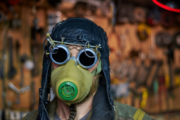 Brodaty mężczyzna w respiratorze i okulary w stylu steampunk, ubrany w płaszcz, koncepcja postapokalipsis. - Zdjęcie, obraz
