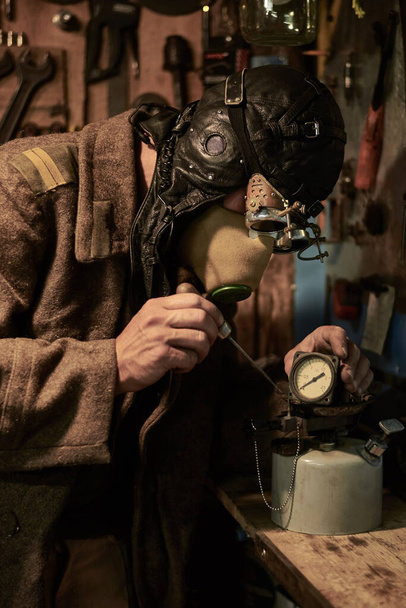 Egy ember lélegeztetőgépben és szemüvegben a steampunk stílusában nyomásmérővel és hengerrel dolgozik, poszt tapokalipszis koncepcióval.. - Fotó, kép