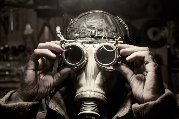 Een man met een masker en een bril in de stijl van steampunk, gekleed in een overjas, postapokalipsis concept. - Foto, afbeelding