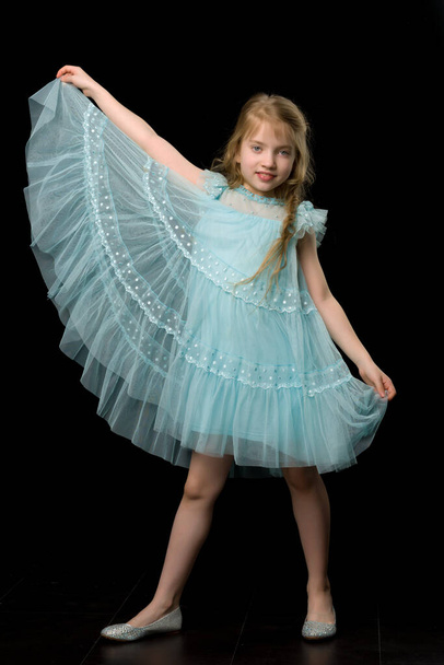 A little girl holds her hands on the edges of the skirt. - Valokuva, kuva