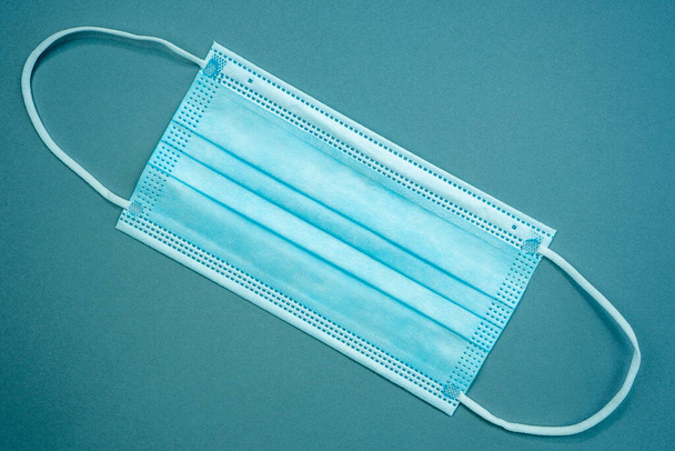 Antybakteryjna maska medyczna koloru niebieskiego na niebieskim tle. Koncepcja ochrony koronawirusów. Wysoka jakość zdjęcia - Zdjęcie, obraz