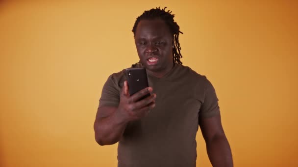 Hombre negro afroamericano sorprendido leyendo un mensaje de texto en el teléfono inteligente - Metraje, vídeo