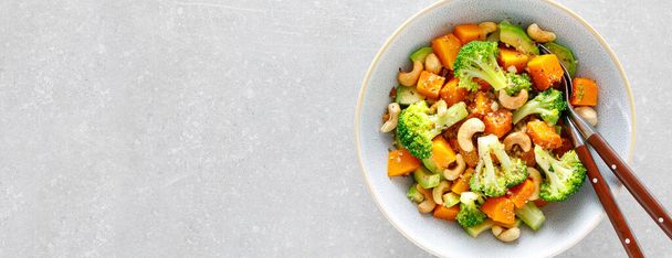 Vegetable salad bowl of broccoli, baked pumpkin, avocado and nuts. Healthy vegan food - Foto, immagini