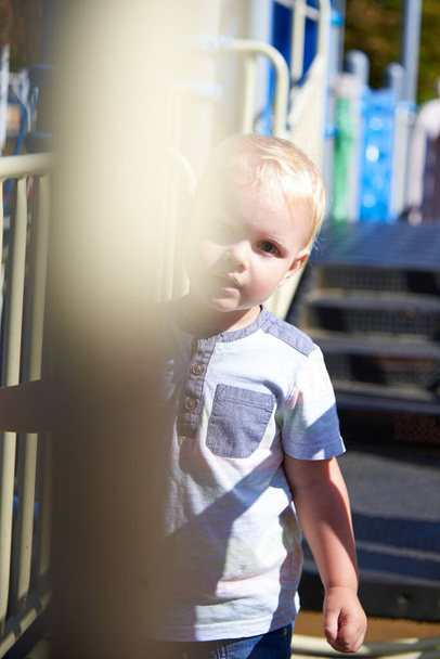 Küçük beyaz çocuk güneşli bir günde oyun bahçesinde oynuyor.. - Fotoğraf, Görsel