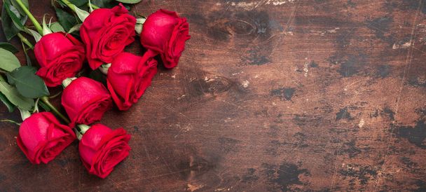 Red rose flowers bouquet on wooden background Valentine's day horizontal banner. Copy space. Top view - Image - Fotografie, Obrázek