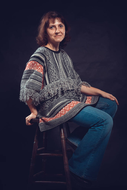 Cheerful 40 years old woman dressed in jeans and poncho studio portrait - 写真・画像