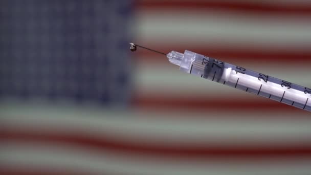 Close-up de uma seringa com a bandeira dos Estados Unidos acenando no fundo - Filmagem, Vídeo