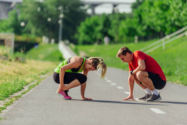 Young caucasian couple taking a break on the running road track and resting after running. - Foto, immagini