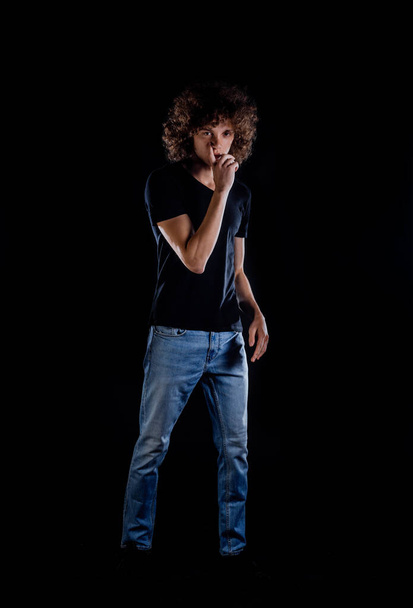 Trendy modern young man dressed in trendy blue jeans and black top - 写真・画像