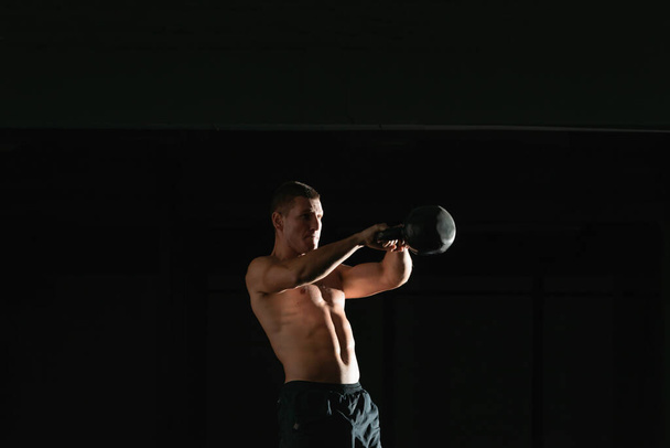 Kontraststarkes Foto eines gesunden Fitness-Typen beim Training mit einer Kettlebell - Foto, Bild