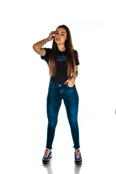 Body shot de una mujer elegante posando en jeans de moda y camiseta negra - Foto, Imagen