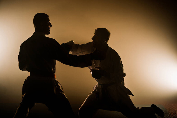 Un athlète avec une ceinture rouge et en karategi effectue un exercice de karaté formel - Photo, image