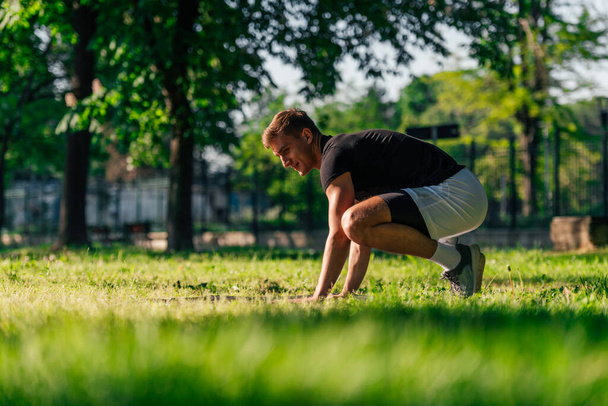 Jovem desportivo praticando postura de corvo ou bakasana, ioga asana, ao ar livre em um parque - Foto, Imagem