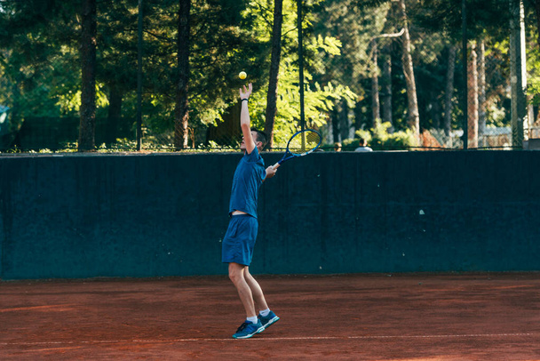 Професійний тенісист подає м'яч на глиняному тенісному корті
 - Фото, зображення