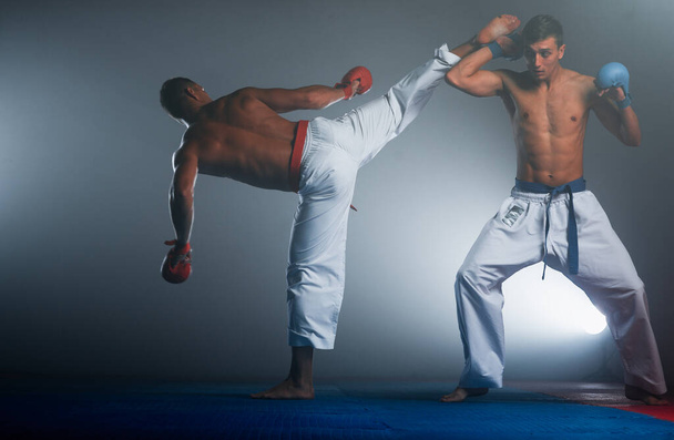 Ένας αθλητής με κόκκινη ζώνη και σε karategi εκτελεί μια επίσημη άσκηση καράτε - Φωτογραφία, εικόνα