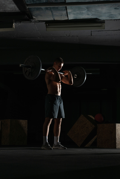 Silhouet van een fit sterke shirtloze atleet die squats doet. Gewicht tillen workout concept. - Foto, afbeelding