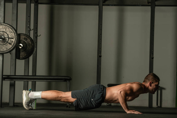Strong male athlete doing push-ups indoors. Close up perspective, healthy lifestyle, fatless body. - Foto, Imagem