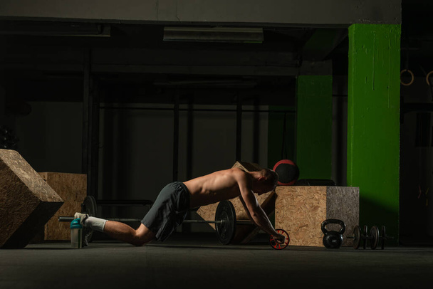 Shirtless pro atleta fazendo russo twist abs treino. Fechar foto de um atleta masculino apto fazendo treinamento indoor. - Foto, Imagem