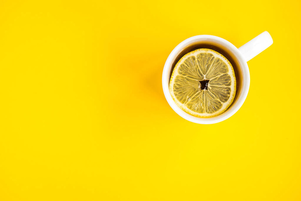 Taza de té caliente con limón sobre fondo amarillo. Enfermedad de Catarral. Temporada de gripe. - Foto, Imagen