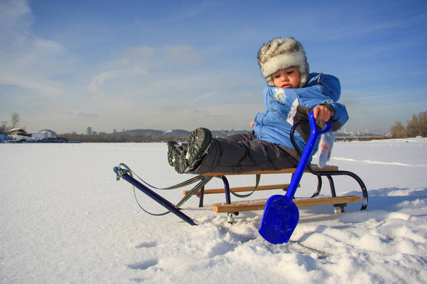 niño pequeño en ropa de invierno con trineo - Foto, Imagen