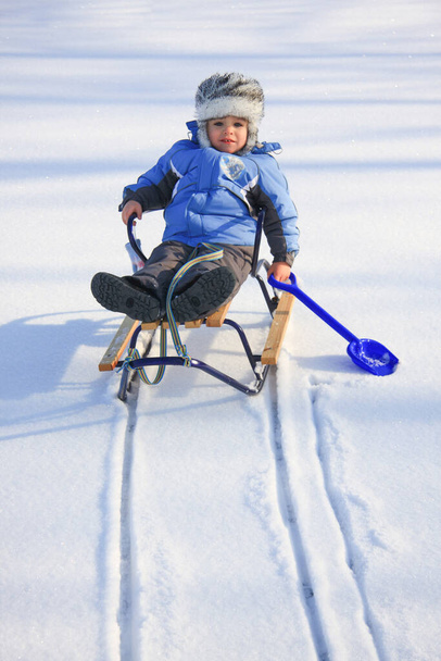 Kleiner Junge in Winterkleidung mit Schlitten - Foto, Bild