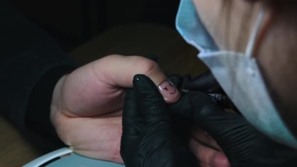 Maniküre - Meister lackiert ein stilistisches Smiley-Gesicht mit schwarzem Nagellack auf den Nagel - Filmmaterial, Video