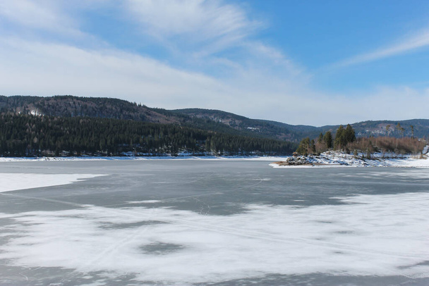 冬の風景の中に凍る湖。氷と雪の背景を持つ山の森の湖。 - 写真・画像