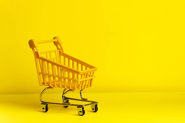 Close-up of shopping trolley on yellow background with some copy space. Investment and business concept. - Φωτογραφία, εικόνα