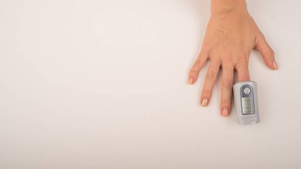 Γυναικείο χέρι με συσκευή μέτρησης κορεσμού. Επίπεδα οξυγόνου αίματος στο coronavirus - Φωτογραφία, εικόνα