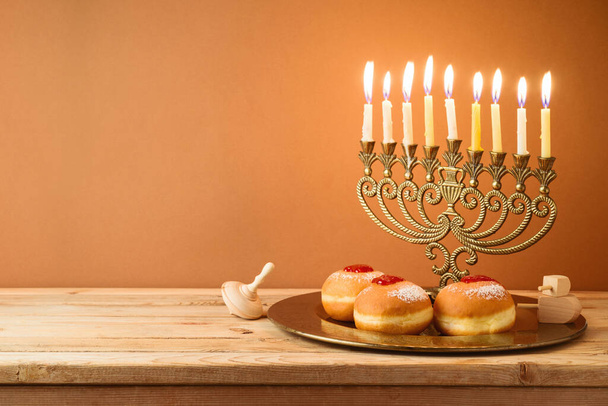 Jewish holiday Hanukkah concept with vintage menorah, candles and traditional donuts on wooden table - Foto, Bild