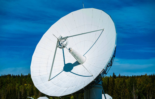 Große weiße Radio-Radarscheibe mit blauem Himmel und Bäumen im Hintergrund. . Hochwertiges Foto - Foto, Bild