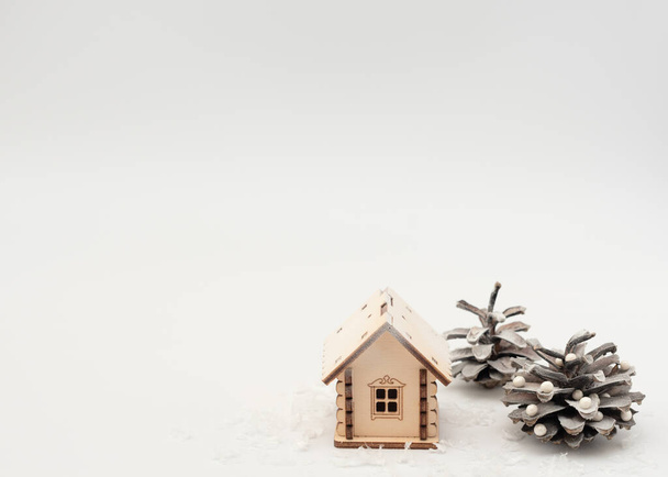 Wooden house in snow with pine cones like decorated Christmas tree on white background. Staying at home during Christmas, New Year  holidays concept. Isolation and coronavirus pandemic. Winter card.  - Zdjęcie, obraz