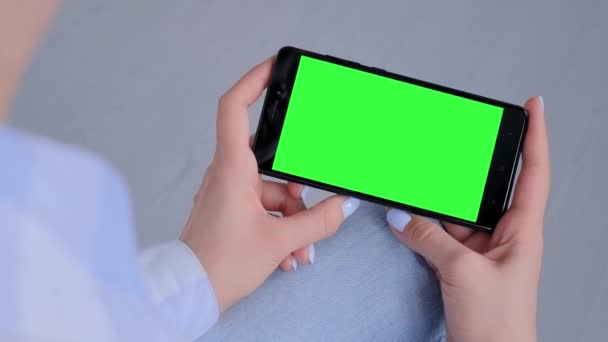 Mujer sosteniendo teléfono inteligente negro con pantalla verde en blanco - concepto de la maqueta - Imágenes, Vídeo