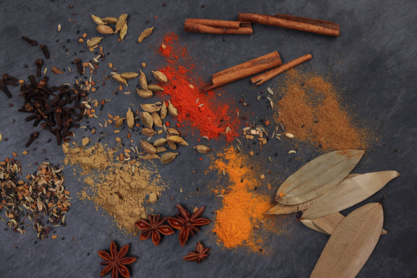 Mélanger variété épice cannelle cardamome clou de girofle laurier en bois piment cumin curcuma propulsé sur fond d'ardoise noire - Photo, image