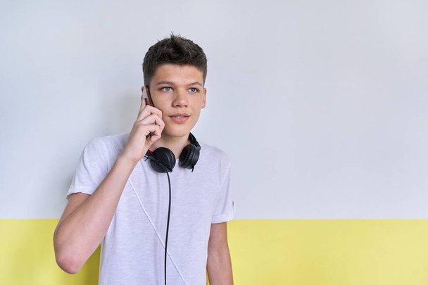 Portrait of student teenager with headphones, talking on mobile phone - Fotoğraf, Görsel